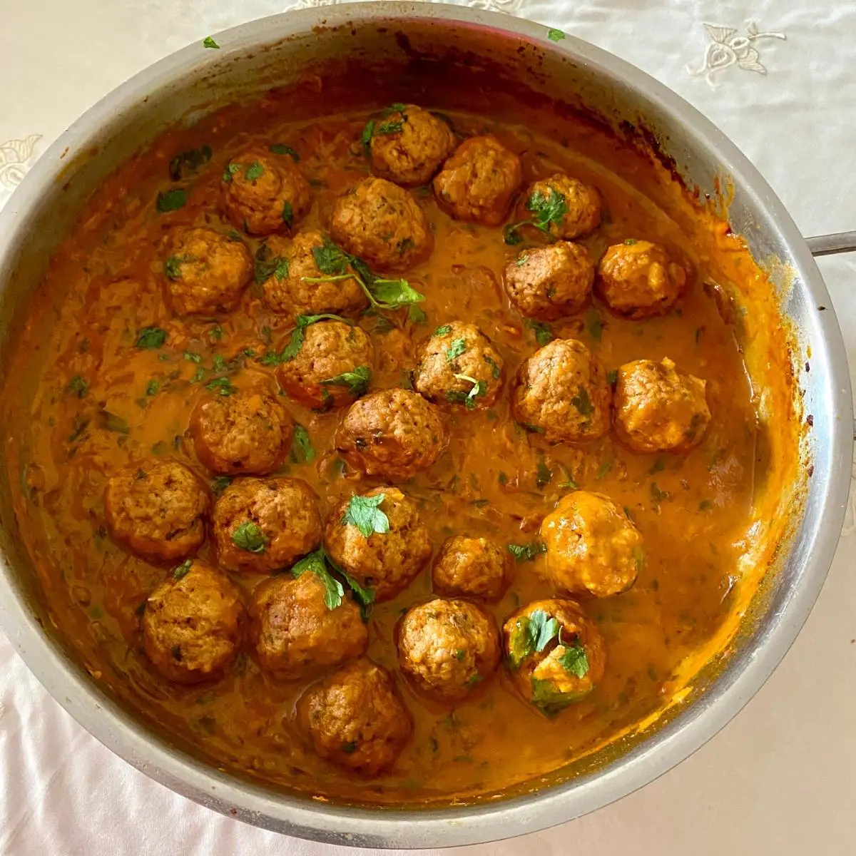 A skillet with curry and meatballs.