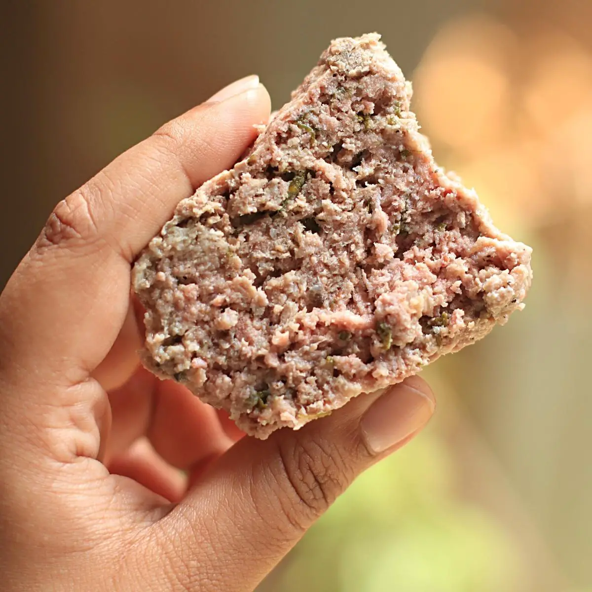 A sliced of meatloaf in a hand.