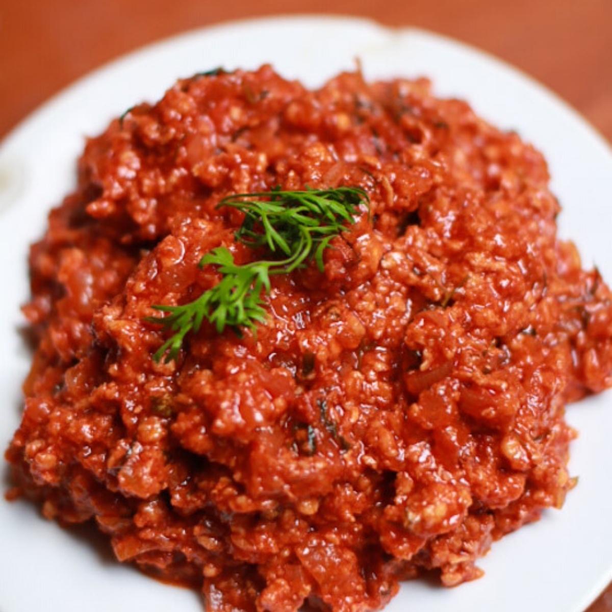 A bowl with ground chicken in vindaloo masala.