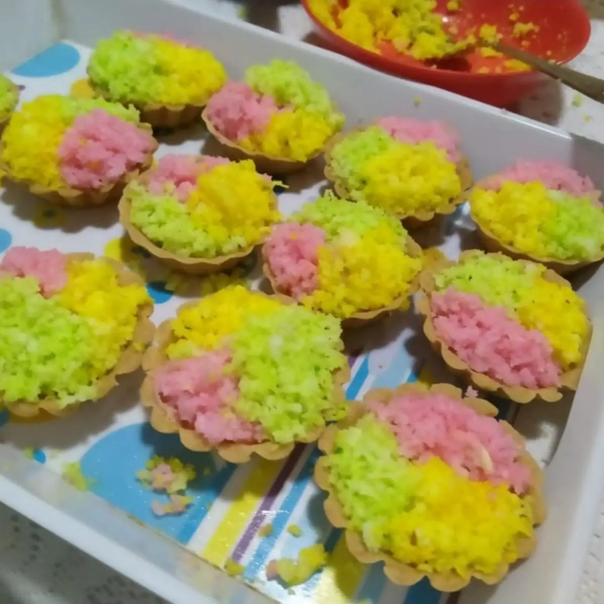 A tray with colored coconut tarts. 