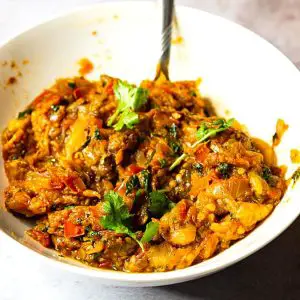 A bowl with roasted eggplant and bottle masala.
