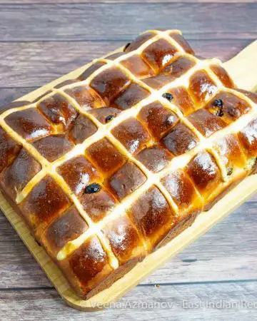 A wooden board with easter buns with a cross.