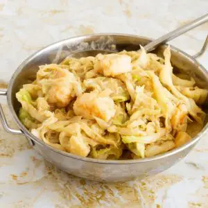 An Indian skillet with cabbage side dish.