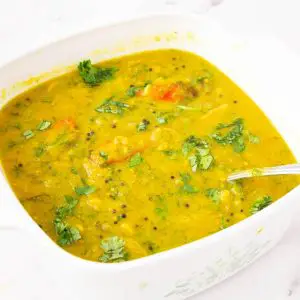 A white dish with yellow lentils dal.
