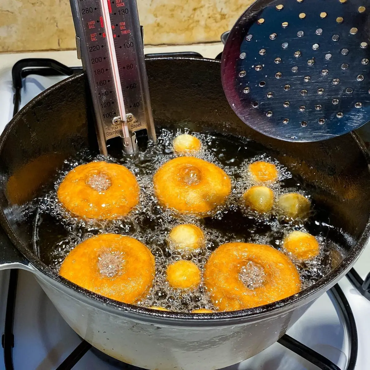 A cast Iron skillet deep frying donuts.