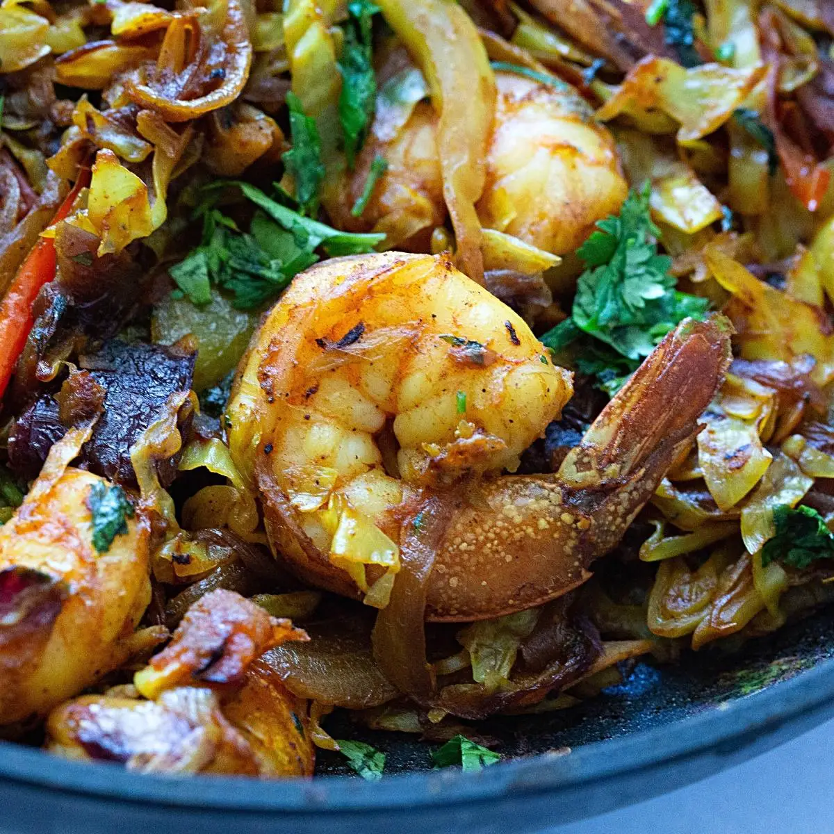 A skillet with prawns and veggies.