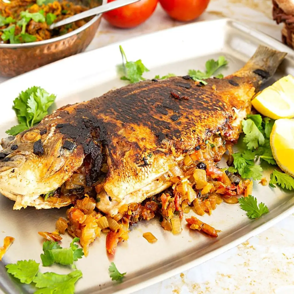 A tray with pan fried fish stuffed with sautéed onions.