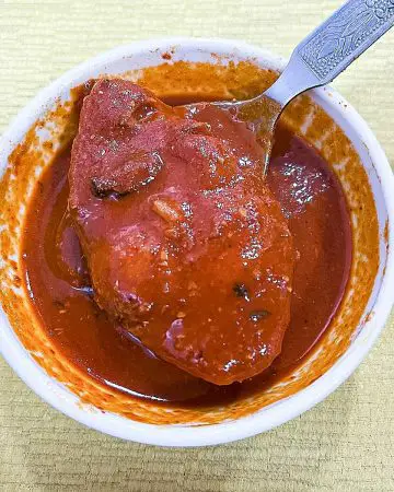 A slice of fish in curry in a bowl.
