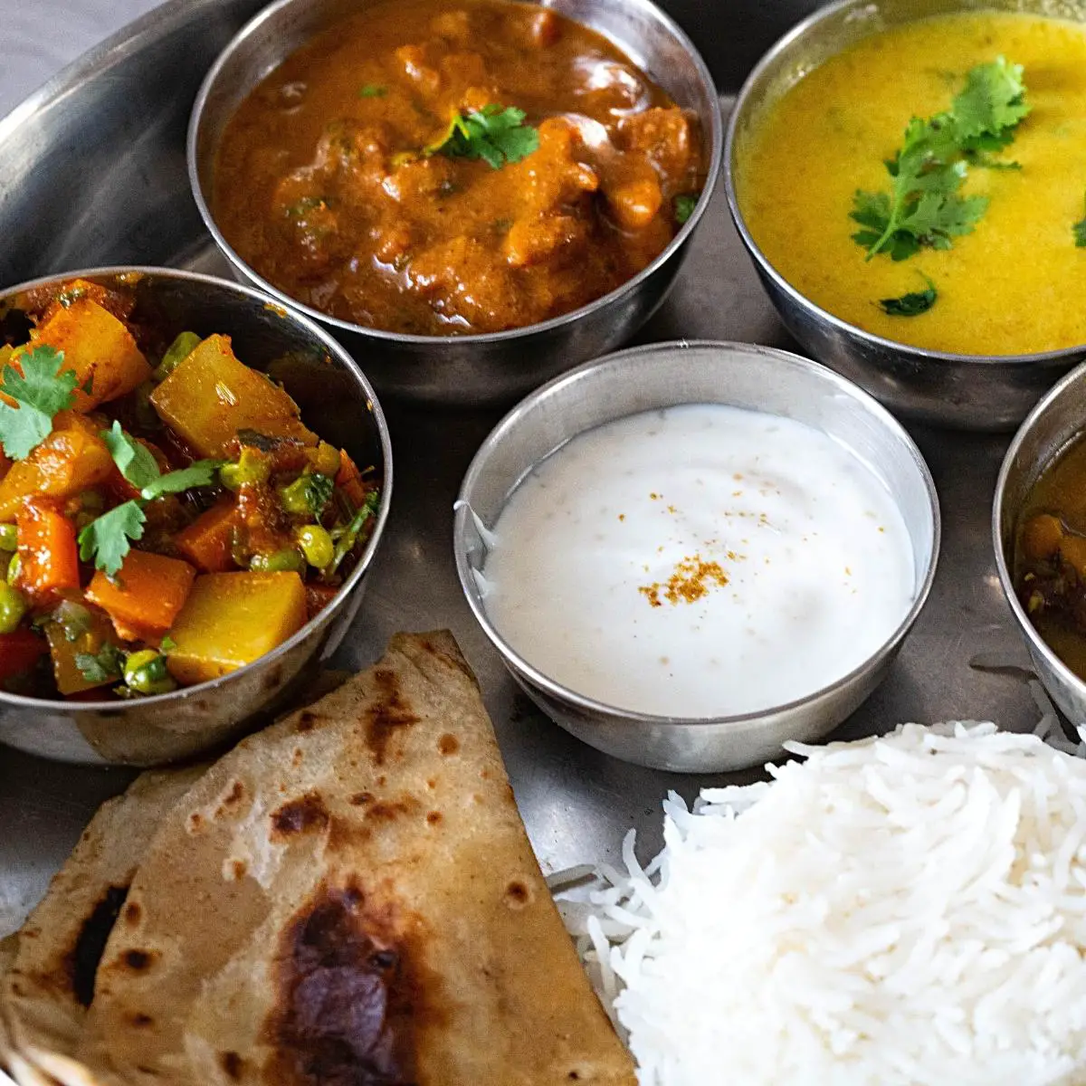 A thali with rice, chapati, and vegetarian dishes.
