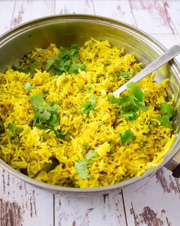Yellow rice with coconut and peas in a skillet.