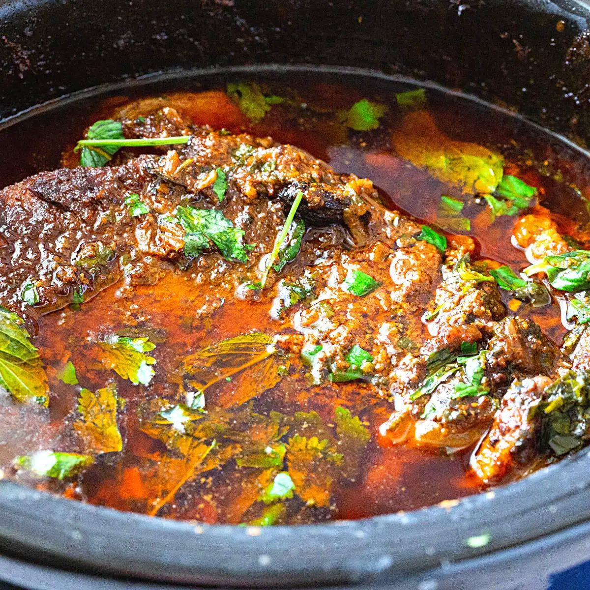 A slow cooker with beef shanks nihari curry.