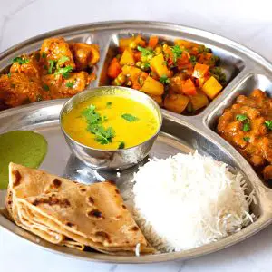Indian thali with chicken and side dishes.