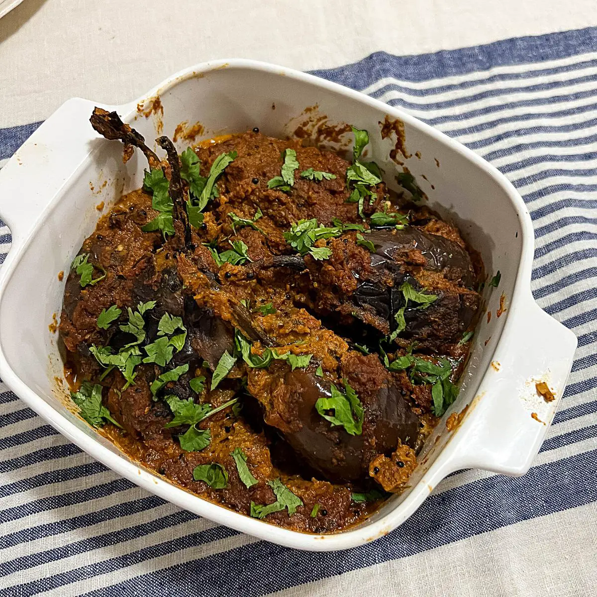 A serving dish with eggplant masala.