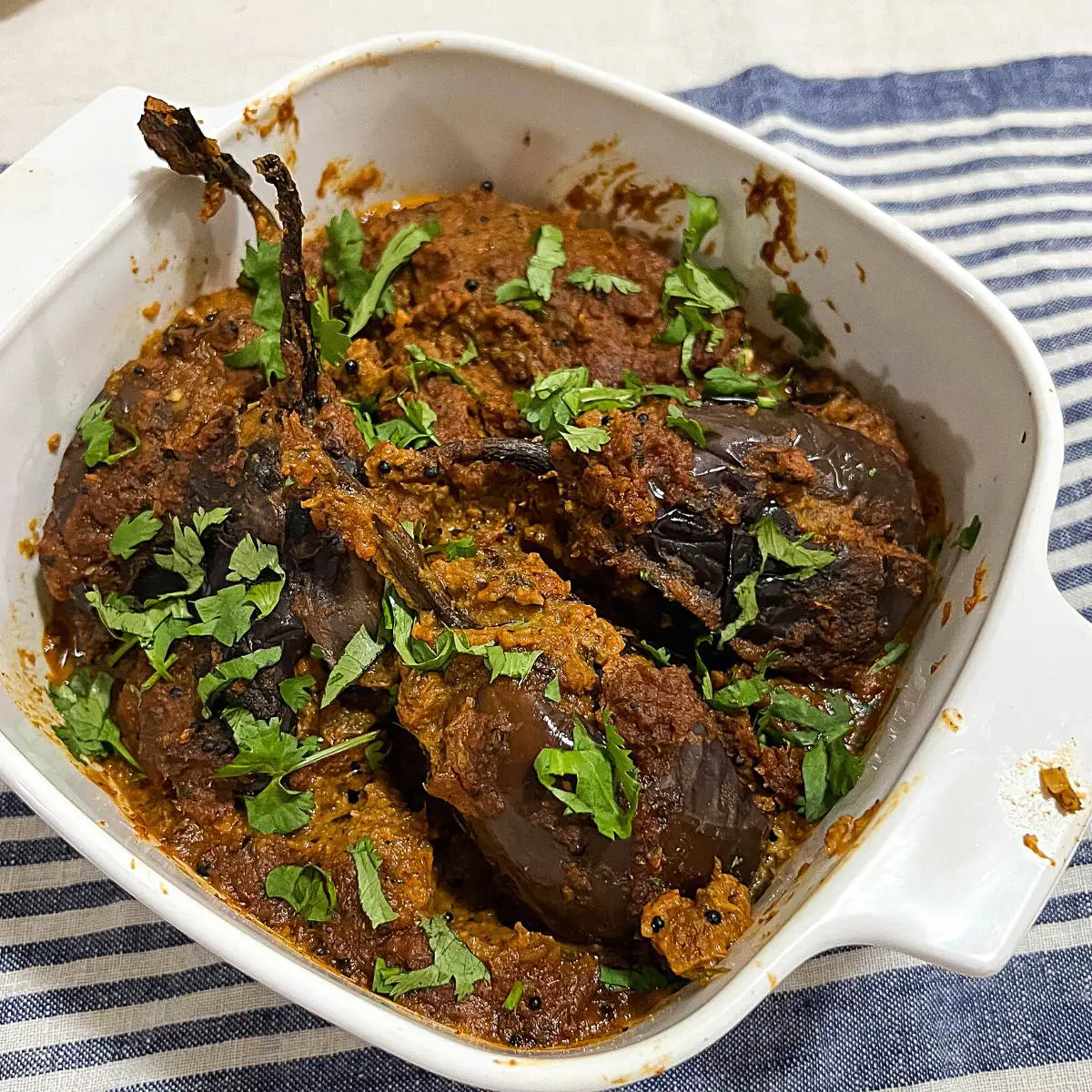 A serving dish with eggplant curry. 