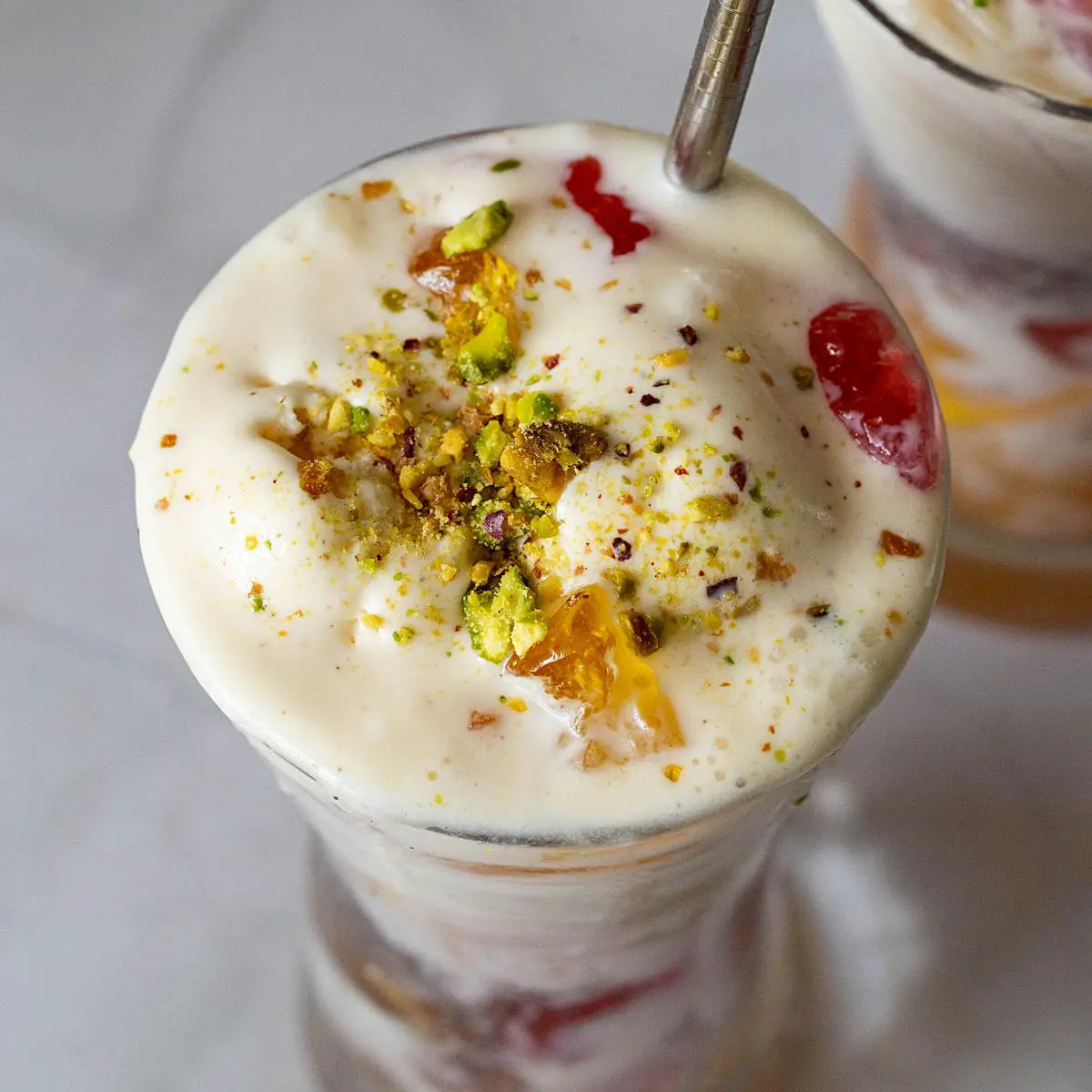 Falooda in glass topped with ice cream.