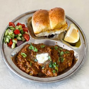 A sectioned Indian plate with pav bhaji.